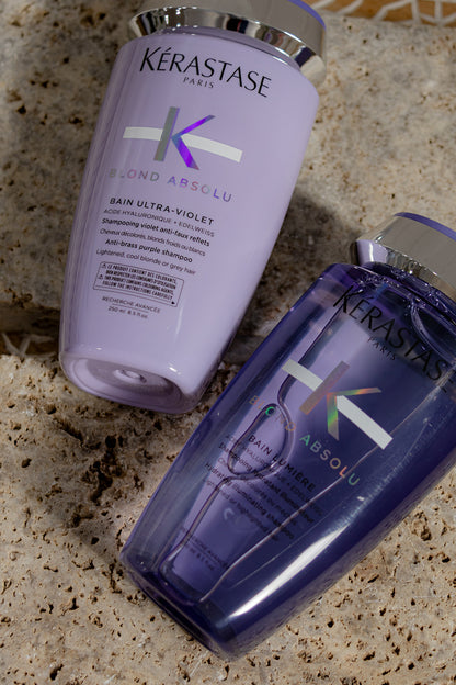 Kérastase Blond Absolu shampoo and conditioner bottles on a textured surface